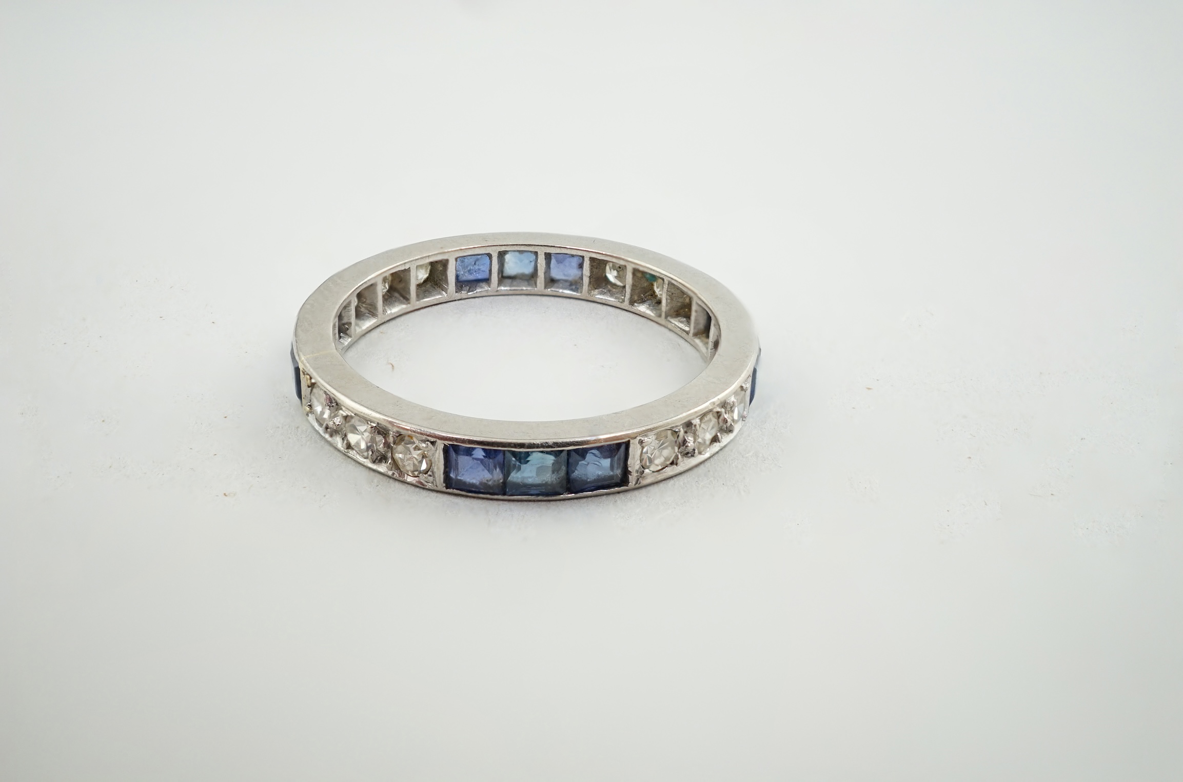 A white gold, twelve stone sapphire and twelve stone diamond set full eternity ring